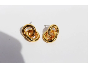 Macro detail of gold plated double circle earrings showing high polish metallic texture