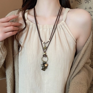 Detail of vintage necklace with multi-element pendants and woven cord on a model