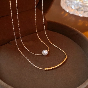 Elegant double-layered gold necklace with a white baroque pearl and curved metal tube pendant