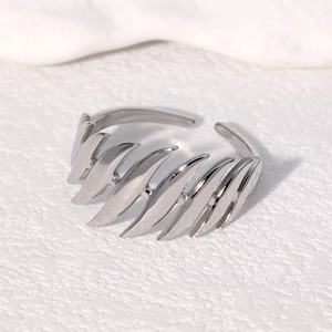 Macro shot of silver feather-shaped layered adjustable ring on white textured stone