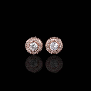 Macro shot of rose gold halo stud earrings with round clear gemstones on black background
