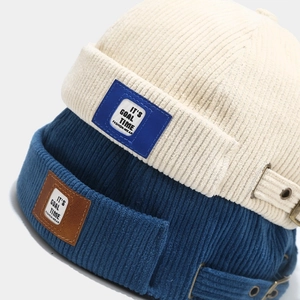 Detail of corduroy docker hats showing side logo labels and metal adjustable buckle straps