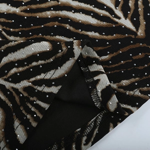 Macro detail of animal print fabric with shimmering rhinestones and hem stitching