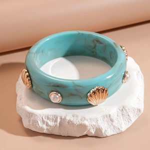 Détail du bracelet en résine marbrée turquoise avec ornements coquillage et perles
