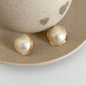 Macro close-up of vintage round pearl stud earrings with polished gold-plated metal base