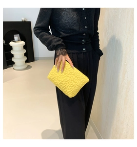 Detailed view of the yellow quilted floral embossed texture on this stylish clutch bag