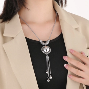Silver hemisphere ball pendant with long tassel chains on a model's beige suit