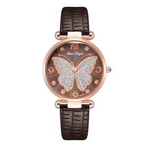 Close-up of rose gold watch dial featuring a glittery butterfly and leather strap