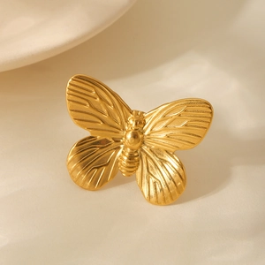 Macro detail of golden butterfly ring showing intricate textures on stainless steel surface