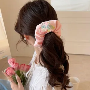 Pink satin scrunchie with strawberry embroidery worn by a model in a sweet Korean style