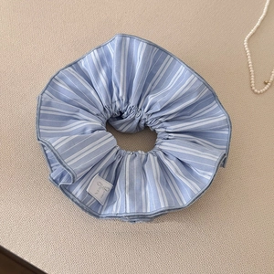 Détail d'un chouchou à rayures bleues et blanches avec étiquette sur fond tissé
