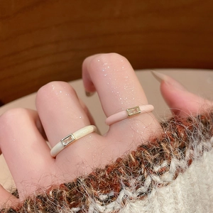 Close-up of cream white and pink enamel rings with rectangular zircon stones on model's fingers