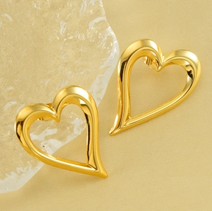 Dettaglio macro di orecchini a cuore traforati placcati oro 18 carats su seta
