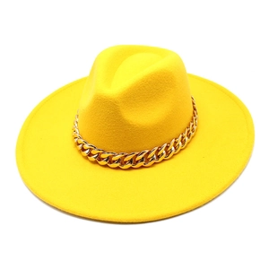 Detail of a bright yellow wide-brim wool fedora hat featuring a chunky gold chain strap