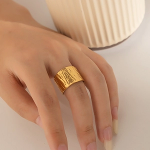 Polished gold wide band ring with hammered texture worn on finger for modern style