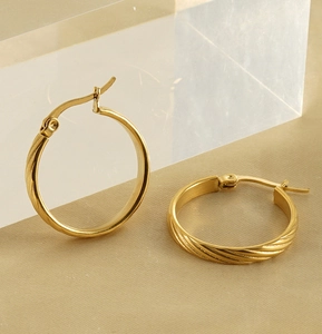 Close-up of golden geometric twisted hoop earrings in 18K stainless steel texture