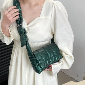 Quilted green padded crossbody bag with adjustable strap shown on white dress model