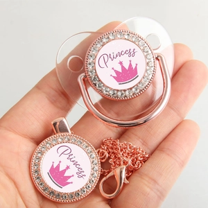 Close-up of rose gold princess crown baby pacifier set with sparkling rhinestones