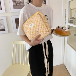 Quilted yellow checkered floral makeup bag with warm quote tag held by model