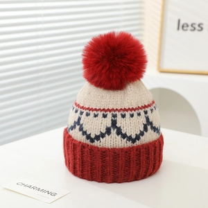 Detail der Winterstrickmütze mit rotem Bommel und dunkelblauen Fair-Isle-Mustern