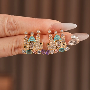 Detailed macro view of gold-plated castle earrings with colorful zircon gemstones