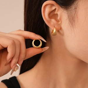 Minimalist matte gold heart geometric hoop earrings worn by a model in a close-up view