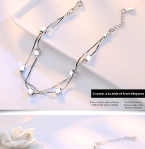 Detail of double-layer snake chain silver bracelet featuring polished cube pendants
