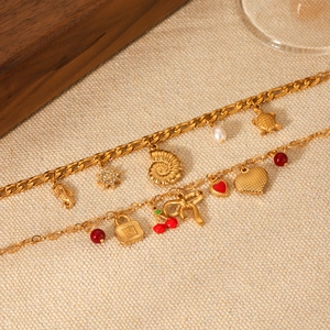 Detail of gold double-layer bracelet with sea shell, turtle and cherry charms