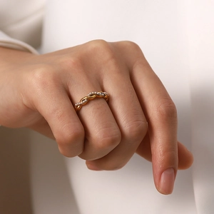 Close-up of twisted titanium steel ring in gold finish with delicate pearl inlay detail