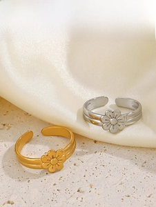 Detail of adjustable flower rings in gold and silver finish on elegant stone surface