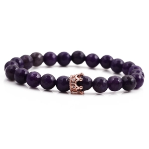 Purple faceted beaded bracelet with a rose gold crown charm on a white background