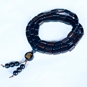 Macro detail of dark brown wooden prayer beads with a golden Fu character and black tassels