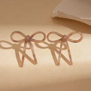 Detailed view of acetate bow earrings in amber marble texture with artistic shadow play