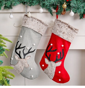 Detail of red and grey knitted Christmas stockings with reindeer appliques hanging on a mantel