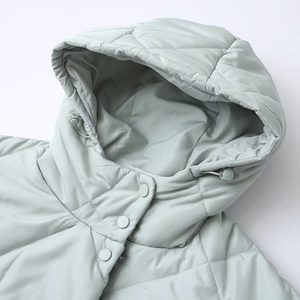 Close-up of mint green quilted jacket featuring drawstring hood and snap button collar