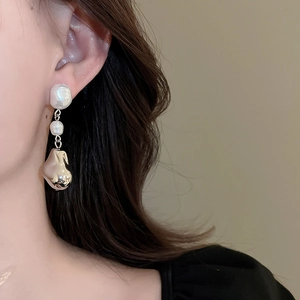Gros plan d'une boucle d'oreille en perle baroque avec pendentif doré de style français