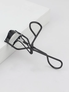 Close-up of black stainless steel eyelash curler with ergonomic handle and silicone pad