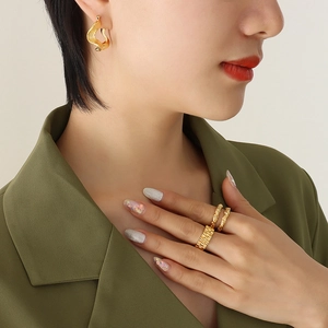 Irregular wave-shaped 18K gold-plated titanium earrings and rings set on a model