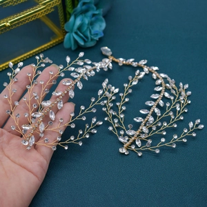 Detail of golden bridal hairpiece with rhinestones and leaf wire weaving on green background