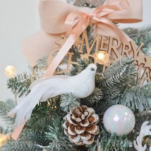 Elegant white feathered bird ornament on a snow-dusted Christmas tree branch decoration