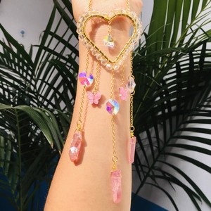 Detail of a butterfly suncatcher bracelet with crystals and gold heart-shaped charm