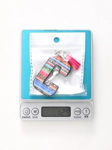Letter C leopard keychain with pink tassel on digital scale weighing 12.9 grams