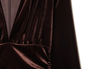 Close-up of deep brown velvet dress featuring V-neckline with pleated texture and side zipper