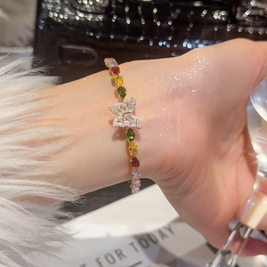 Dettaglio del bracciale a farfalla in zircone con pietre colorate sul polso di una donna