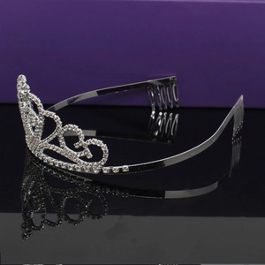 Macro detail of silver tiara showing intricate heart patterns and sparkling rhinestones