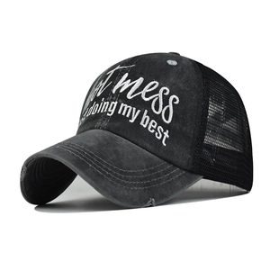 Close-up of distressed black mesh baseball cap with embroidered Just a mess slogan detail