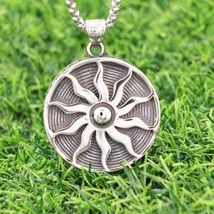 Nordic sun totem necklace in silver stainless steel on green grass background