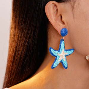 Orecchini a stella marina in rafia intrecciata blu indossati da una modella