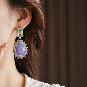 Gros plan de boucles d'oreilles vintage avec cristaux violets et verts et accents de diamants