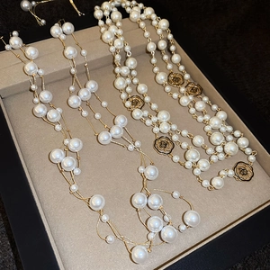 Detail view of gold layered pearl necklaces with black enamel camellia flower charms